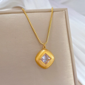 Macro view of gold square pendant with clear zircon inlay and classic box chain