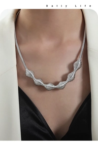 Detail of silver twisted chain necklace with textured spiral links on a white suit