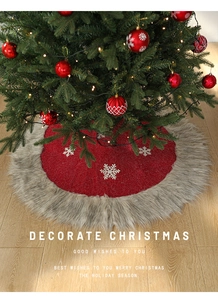 Macro detail of red Christmas tree skirt with white snowflake and grey faux fur trim