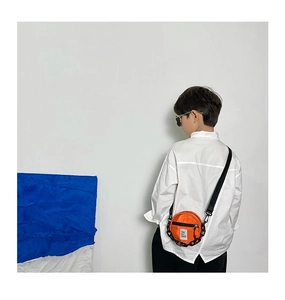 Détail macro du sac rond en nylon orange vif avec chaîne noire et bandoulière