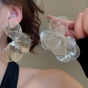 Détails macro de grandes boucles d'oreilles fleurs argentées aux pétales ajourés chic