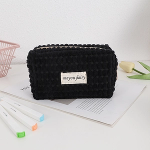Detail of black bubble waffle fabric makeup bag with white label and zipper closure