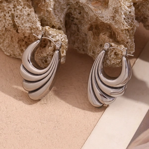 Macro shot of silver wave-shaped earrings with layered design on natural stone base