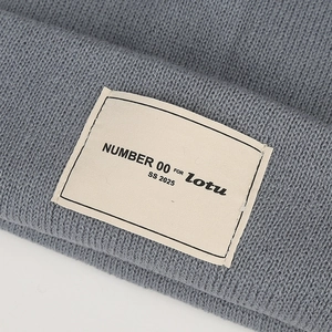 Detail der graublauen Rippstrickmütze mit Textur und dem Logo-Markenetikett