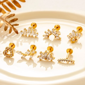 Golden stainless steel labret stud set with zircon heart and crown shapes on a tray