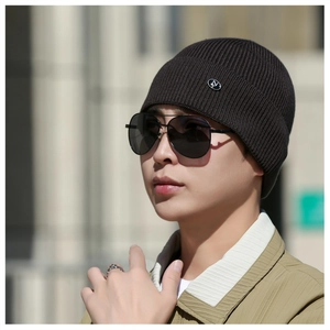 Detail of soft ribbed knit beanie with small round metal logo tag on folded brim