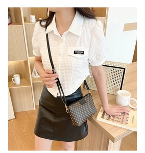 Detail of vintage patterned crossbody bag with gold buckle on white waffle texture shirt