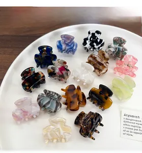 Mini acetate hair claw clips in various patterns displayed on a white round plate