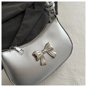 Detail of silver metallic handbag featuring a stylish 3D bow and smooth PU leather finish