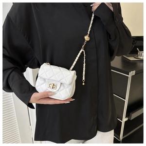 Detailed close-up of quilted white mini bag with golden twist lock and chain strap