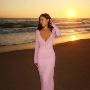 Detail of pink ruffle dress with deep V-neck and long sleeves on a sunset beach