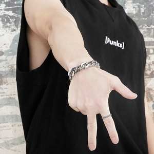 Detail view of bold steel curb chain bracelet and textured ring in punk style