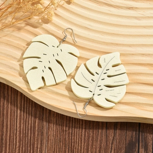 Bohemian beige wooden monstera leaf earrings with carved texture on a natural tray