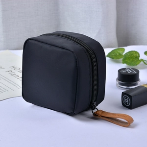 Portable black nylon lipstick pouch with leather zipper pull and minimalist aesthetic