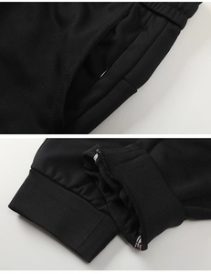Detail of black knit sports pants featuring side pockets and ribbed cuffs