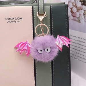 Close-up of a purple bat plush keychain with laser wings on a stylish handbag
