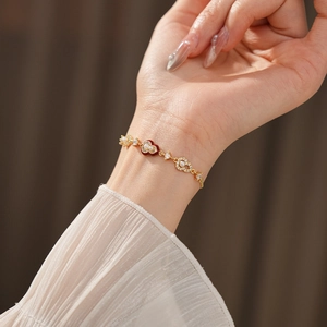 Detail of gold heart bracelet with red enamel, pearls, and zircons on model's wrist