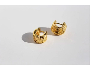 Macro shot of gold hoop earrings featuring textured lava metallic surface design