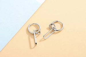 Macro shot of silver geometric earrings with rectangular and oval links on a dual-tone background