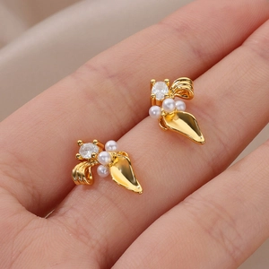 Close-up of 18K gold-plated heart earrings with zircon and white pearls on hand