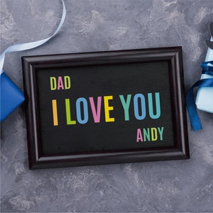 Detail of wooden picture frame with Dad I Love You text on a textured stone background