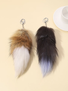 Detail showing two oversized faux fur fox tail keychains with silver lobster clasps
