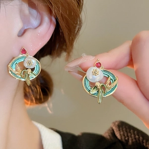 Detail of vintage French gold pearl flower earrings with red gemstone and green enamel