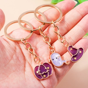 Close-up of metal Halloween keychains featuring purple pumpkin, ghost and witch hat charms