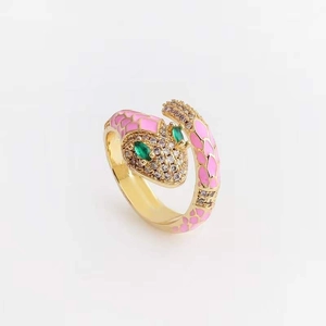 Gold snake ring with pink enamel and green gemstone eyes on white background