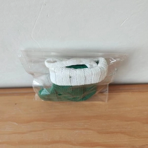 Detailed macro view of a green and white knit mini Christmas stocking in transparent bag