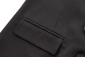 Gros plan détaillé sur le tissu sergé noir et les finitions de la poche de ce blazer chic