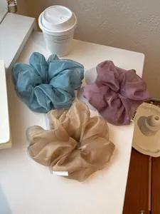 Tre grandi elastici per capelli in organza blu, viola e champagne su sfondo