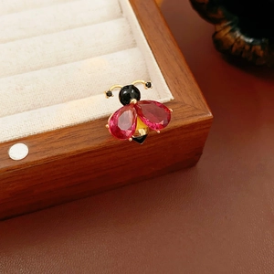 Close-up of vintage enamel bee brooch with red gems and gold frame on jewelry box