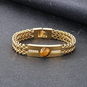 Macro detail of men's gold stainless steel bracelet with tiger eye stone and zircons