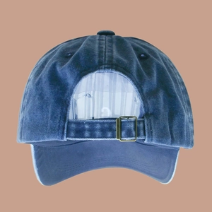 Detail view of washed denim baseball cap featuring an adjustable metal buckle and blue fabric