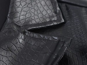 Close-up of black PU leather with embossed crocodile texture on a long trench coat