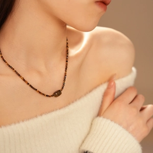Macro shot of tiger eye beaded necklace with oval gemstone on a model's neck