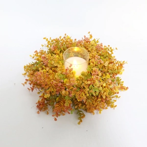 Close-up of orange eucalyptus leaf wreath with a glass candle holder for autumn table decor