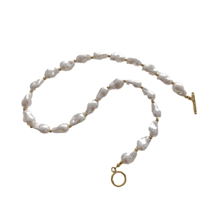 Elegant baroque pearl necklace with gold spacers and vintage toggle clasp on white background