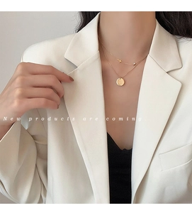 Detailed view of layered 18K gold-plated titanium necklace with round charm and cross
