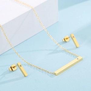 Macro detail of golden bar pendant and matching stud earrings set with small diamond accents