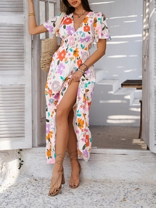 Detail view of a V-neck floral dress with a high-slit and vibrant bohemian print