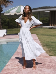 Detail of white deep V-neck maxi dress with puff sleeves and textured fabric on model
