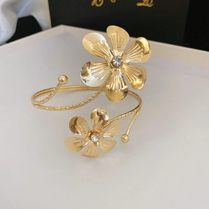 Detail of adjustable gold-plated floral cuff with textured petals and zircon center