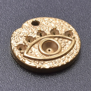 Detailed macro view of gold-plated evil eye pendant with hammered texture and stone settings