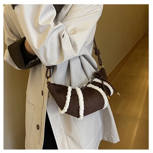 Detail der dunkelbraunen Wildleder-Hörnchen-Tasche mit weißem Lammfellbesatz und Lederriemen