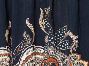Détail macro du tissu bleu foncé d'un chemisier aux motifs floraux ethniques orange