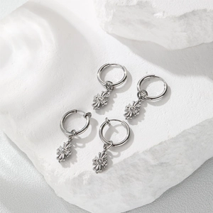 Macro detail of silver star pendant hoop earrings with zircon on white rock background