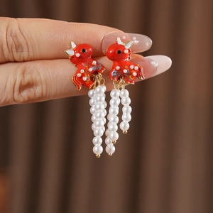 Close-up of vintage enamel calf earrings with elegant pearl tassel charms and gold finish