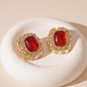 Gros plan de boucles d'oreilles vintage avec pierre rouge et strass sur socle blanc